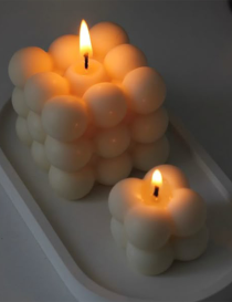 Lit premium milky white bubble candles glowing on a minimalist white tray.