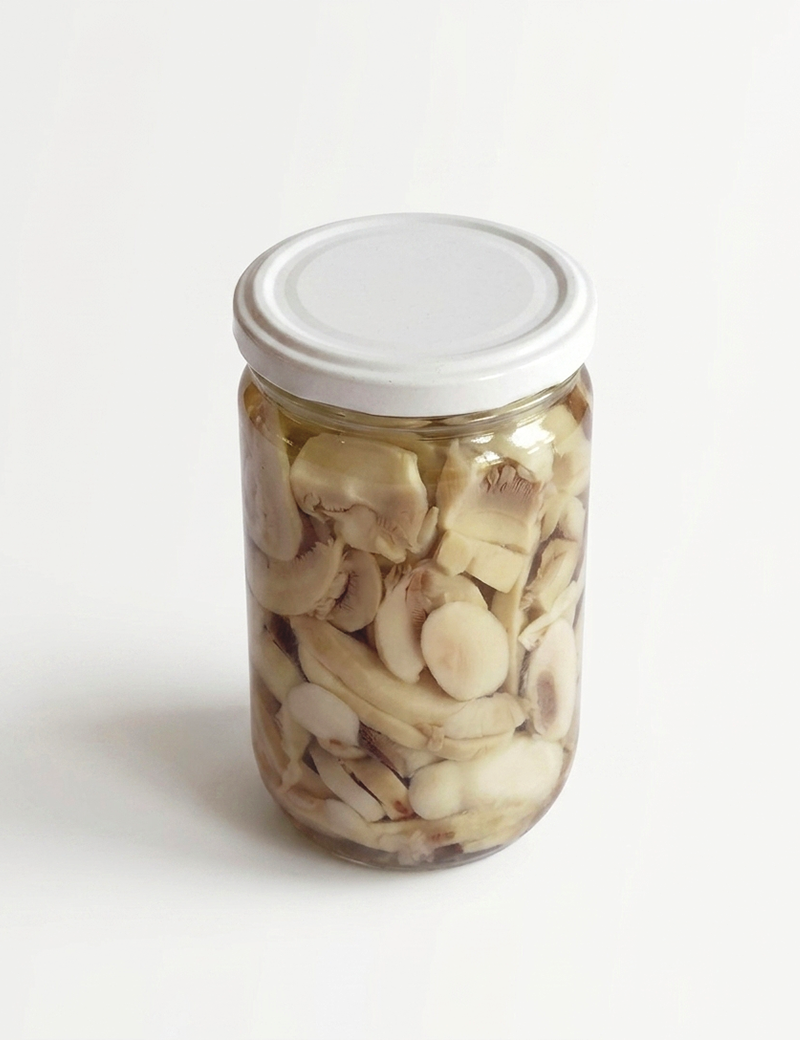 Front top view of a sterile glass jar filled with sliced premium King Oyster mushrooms, white lid, soft shadow.