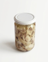 Front top view of a sterile glass jar filled with sliced premium King Oyster mushrooms, white lid, soft shadow.