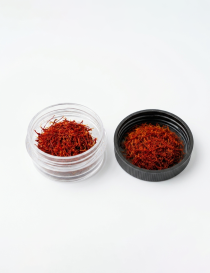 Top-front view of premium Super Negin saffron in glass container with lid, on white background.