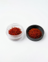 Top-front view of premium Super Negin saffron in glass container with lid, on white background.