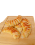 A pile of fresh Syrian Halloumi croissants with sesame seeds on a wooden serving board