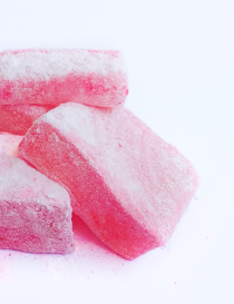 Close-up shot of soft and chewy pink saffron loukoum delights dusted with fine sugar.