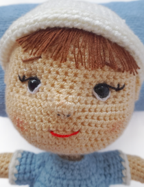 Close-up shot of Nano crochet doll awake face with embroidered eyes and brown bangs