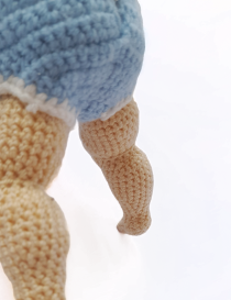 Detailed close-up view of hand-knitted crochet legs on Nano baby doll