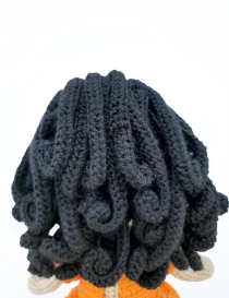 Detailed back view of dark curly hair on handmade crochet doll Lora