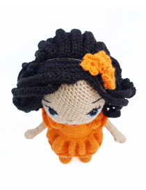 Top view of handmade Lora crochet doll with orange dress and hair bow
