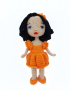 Full standing view of Lora handmade crochet doll in bright orange dress