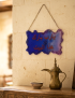 The resin blessing plaque hanging on a stone wall inside a warm, traditional Syrian home entrance.