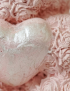 Macro detail of the shimmering silver heart held by the handmade bear
