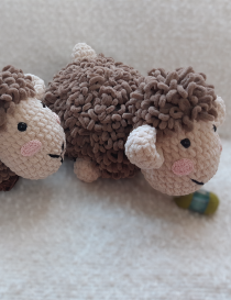 A pair of handmade crochet sheep toys by Saja Handmade, in brown and cream plush velvet yarn, on a soft white rug.