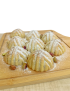 Fresh Syrian pistachio maamoul dusting with powdered sugar on a wooden board - Al Amin Kitchen