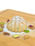 Single handcrafted Syrian pistachio maamoul garnished with whole pistachios and powdered sugar