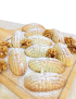 Freshly baked handcrafted Syrian walnut maamoul dusted with powdered sugar served on a wooden cutting board