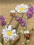 Detailed shot of handcrafted white daisies and purple lavender ribbon embroidery.