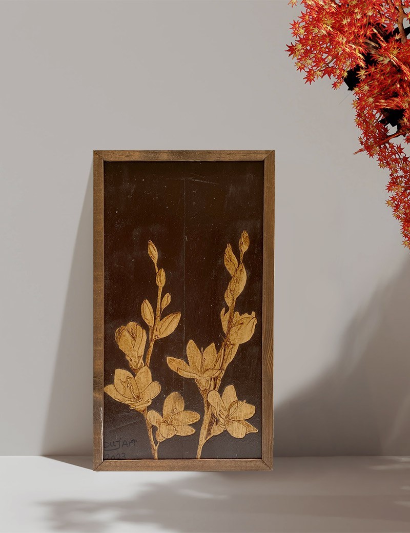Handcrafted woodburned tulip art on a table next to red maple leaves.