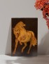 Hand-etched horse woodburning art displayed on a shelf with autumn leaves.