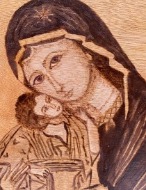 Detailed closeup of pyrography technique on Virgin Mary's face.