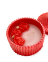 Close-up of scented candle wax with three red wax roses and dried flowers.