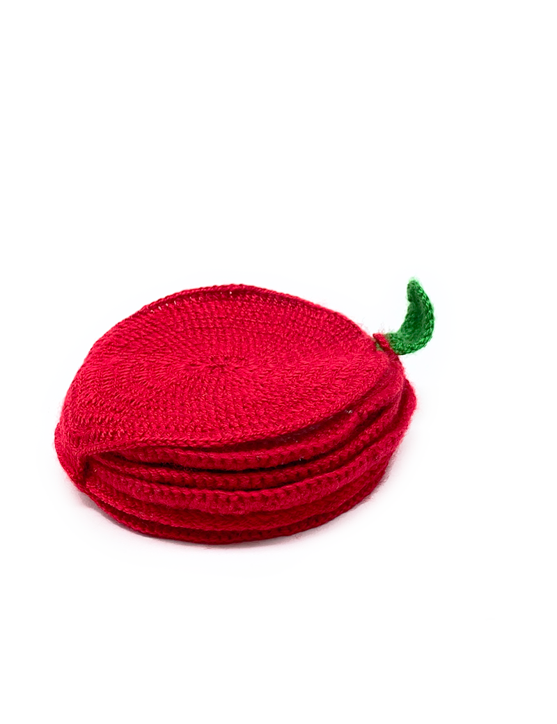 Stacked handmade crochet apple coasters forming a whole red apple with a green leaf.