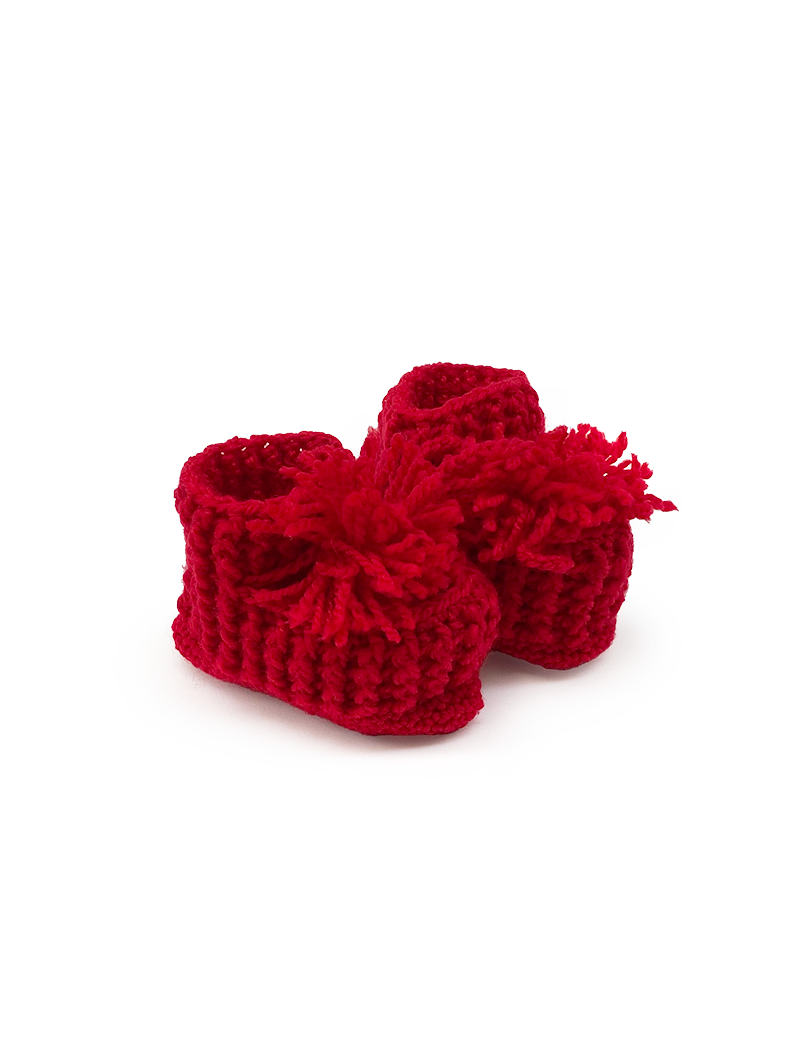Pair of handmade red crochet kids' slippers with pom-poms on a white background.