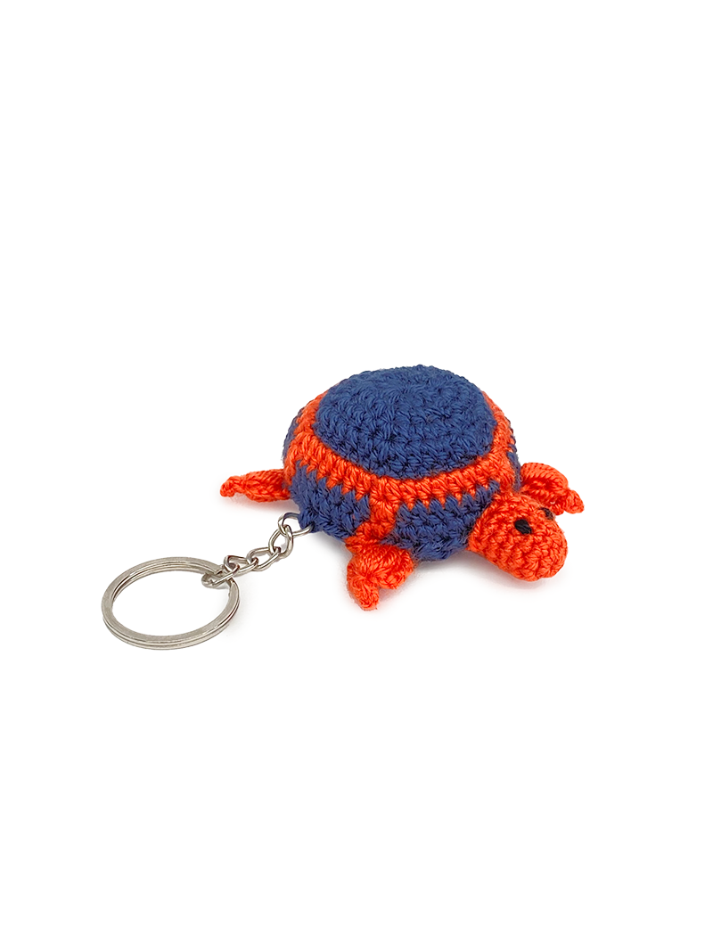 Side profile of a blue and orange handmade amigurumi turtle with metal key ring.