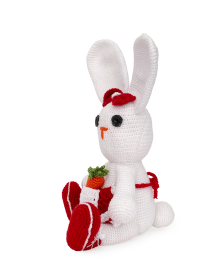 Side profile of sitting crochet rabbit toy in red outfit.