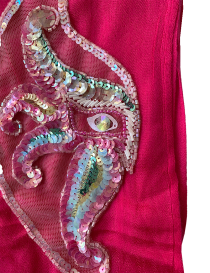 Detailed view of iridescent sequins and beadwork on a handmade mask-shaped embroidery.