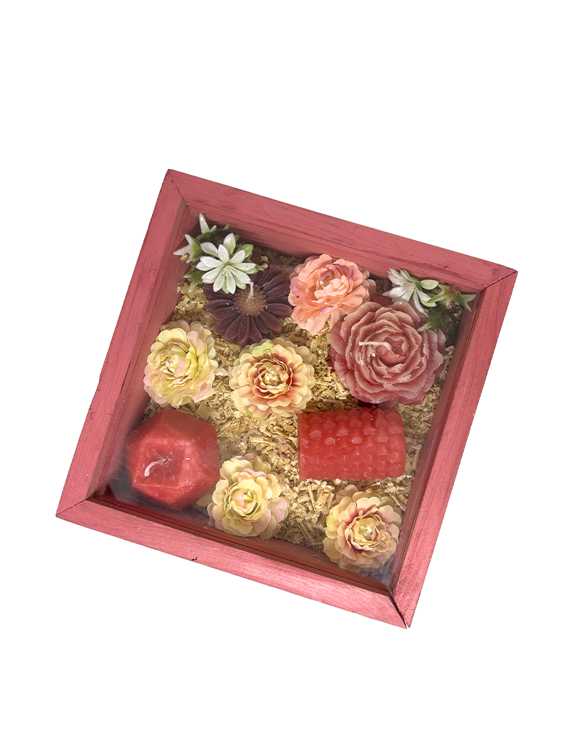 Crimson red wooden gift box with sliding glass lid containing floral-shaped wax candles.