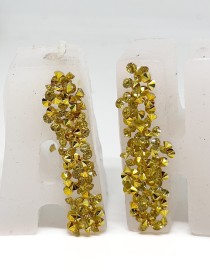 White wax letter candles with gold glitter accents spelling out a word on a white surface.