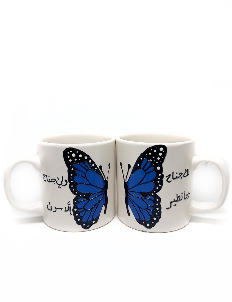 Pair of white ceramic mugs with a blue butterfly design and Arabic calligraphy.