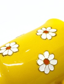 Hand-painted yellow ceramic mug with white daisy floral design and decorative handle.
