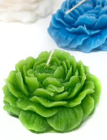 Green rose-shaped candle with silver leaf accents and white wick.