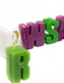 A line of colorful letter candles spelling a custom word for cake decoration.