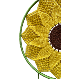 Side view of the crochet sunflower attached to a green-wrapped hoop.