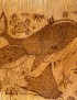 Close-up of woodburned whale and crab details.