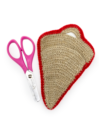 Beige crochet scissor case with red embroidered edge next to pink handle scissors.