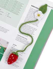 Handmade crochet strawberry bookmark lying on an open craft magazine.