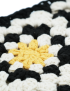 Black and white square handmade crochet handbag with yellow center and gold circular metal handles.