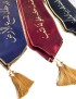 Close-up of maroon and blue satin graduation stoles with gold Arabic calligraphy and tassels.