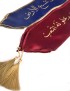 Close-up of maroon and blue satin graduation stoles with gold Arabic calligraphy and tassels.