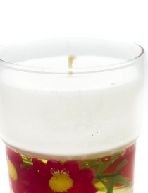 White wax candle in glass jar with pink flowers embedded in a gel base.