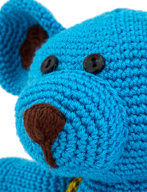 Detailed macro shot of blue bear's face with brown embroidered nose and button eyes.