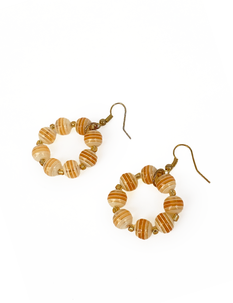 Pair of circular hoop earrings made with striped orange and cream glass beads.