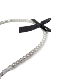 Detail view of white pearls and black ribbon bow hair accessory.