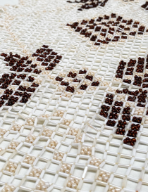 Close-up of the intricate beadwork and fisherman's thread weaving on the brown flower motif.