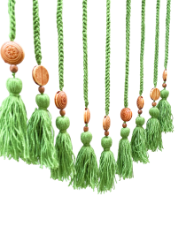 Close-up of carved wooden floral beads and textured green yarn tassels.