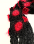 Detailed view of black tassels and red floral squares on a crochet scarf.