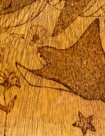 Macro detail of a woodburned stingray and starfish.