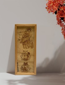 A4 woodburned tableau of forest animals leaning against a wall next to red autumn leaves.